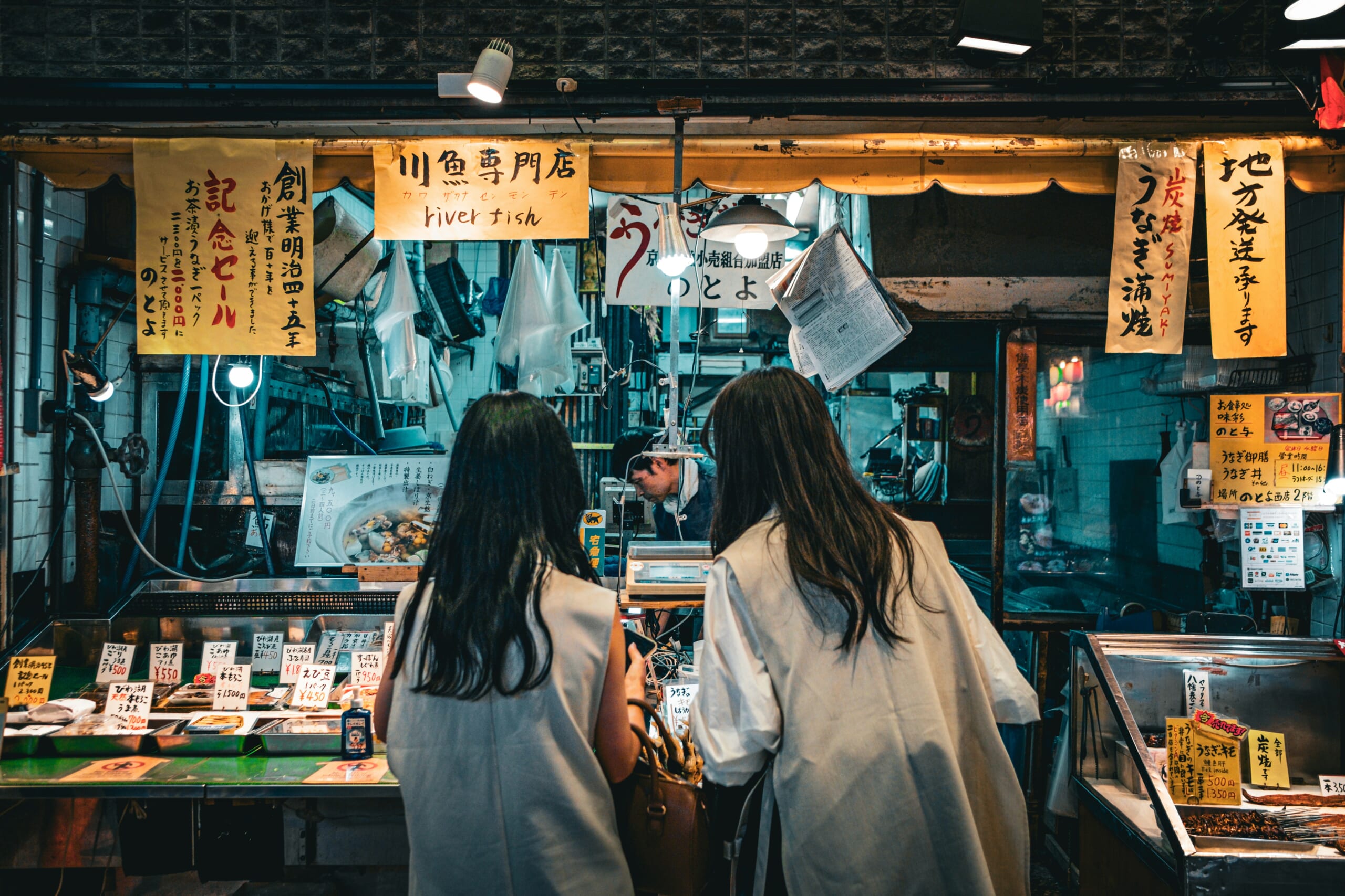Customers looking at products and price signs at a fish shop in Kyoto's Nishiki Market