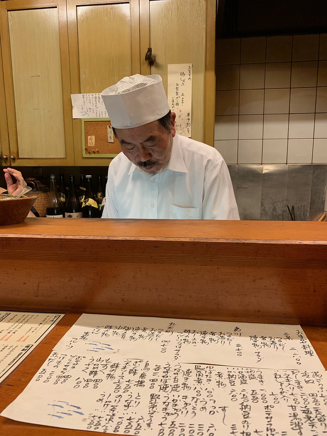 A proprietor preparing food behind the counter of a small Kyoto restaurant