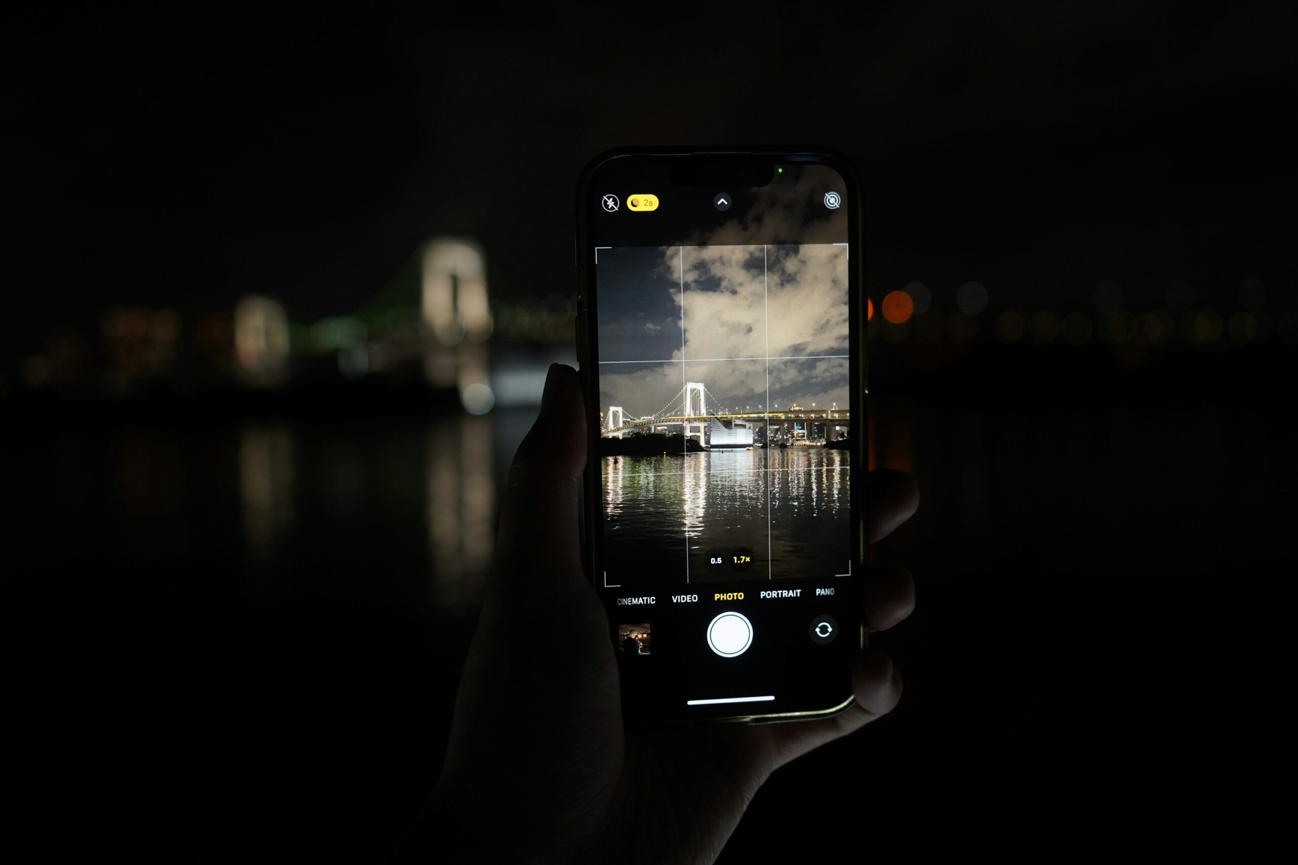 Hands photographing Tokyo at night with a smartphone