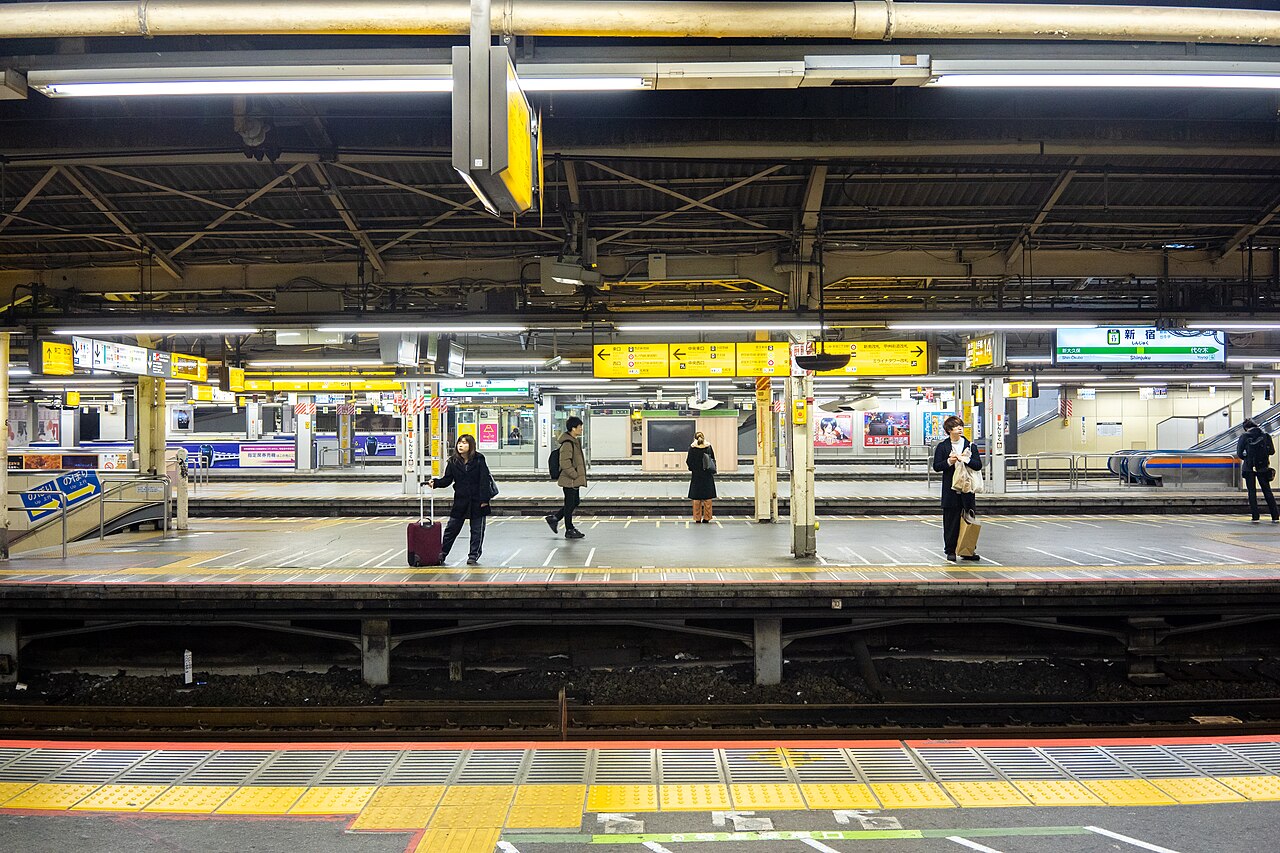 People waiting on a Shinjuku Station platform at night