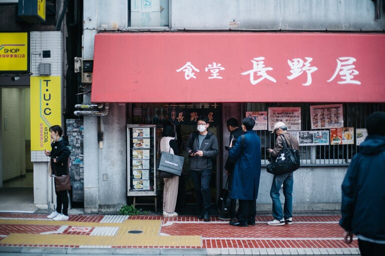 Visitors checking information at a restaurant entrance in Shinjuku