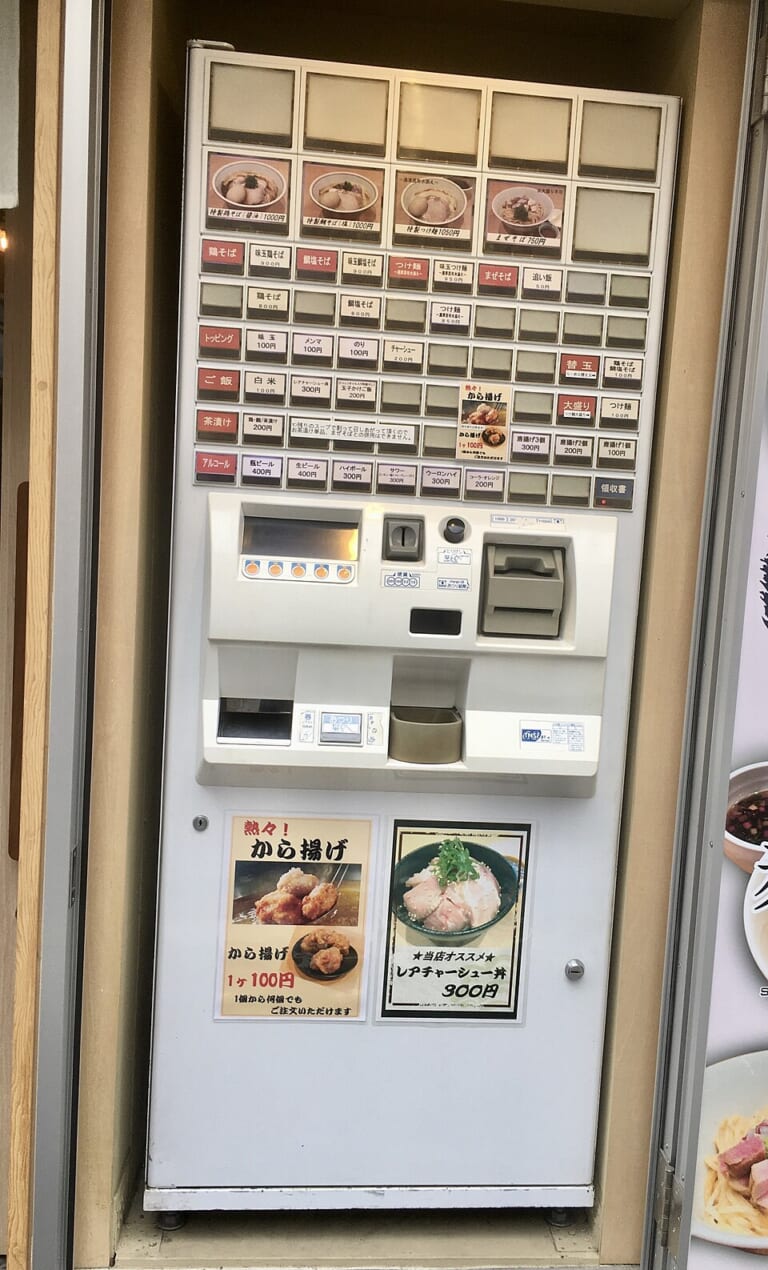 A ramen meal-ticket machine with menu photographs and buttons