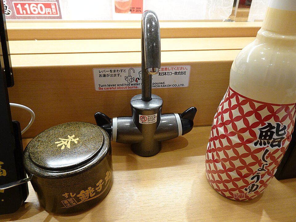 Tea cups and a hot-water dispenser on a sushi restaurant counter