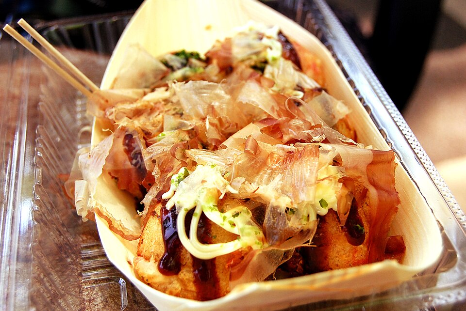 Takoyaki topped with green seaweed in a boat-shaped tray