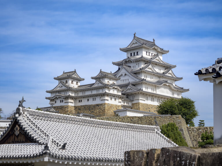 Himeji Castle's white keep seen from near the Nishinomaru South Gate ruins beneath a blue sky