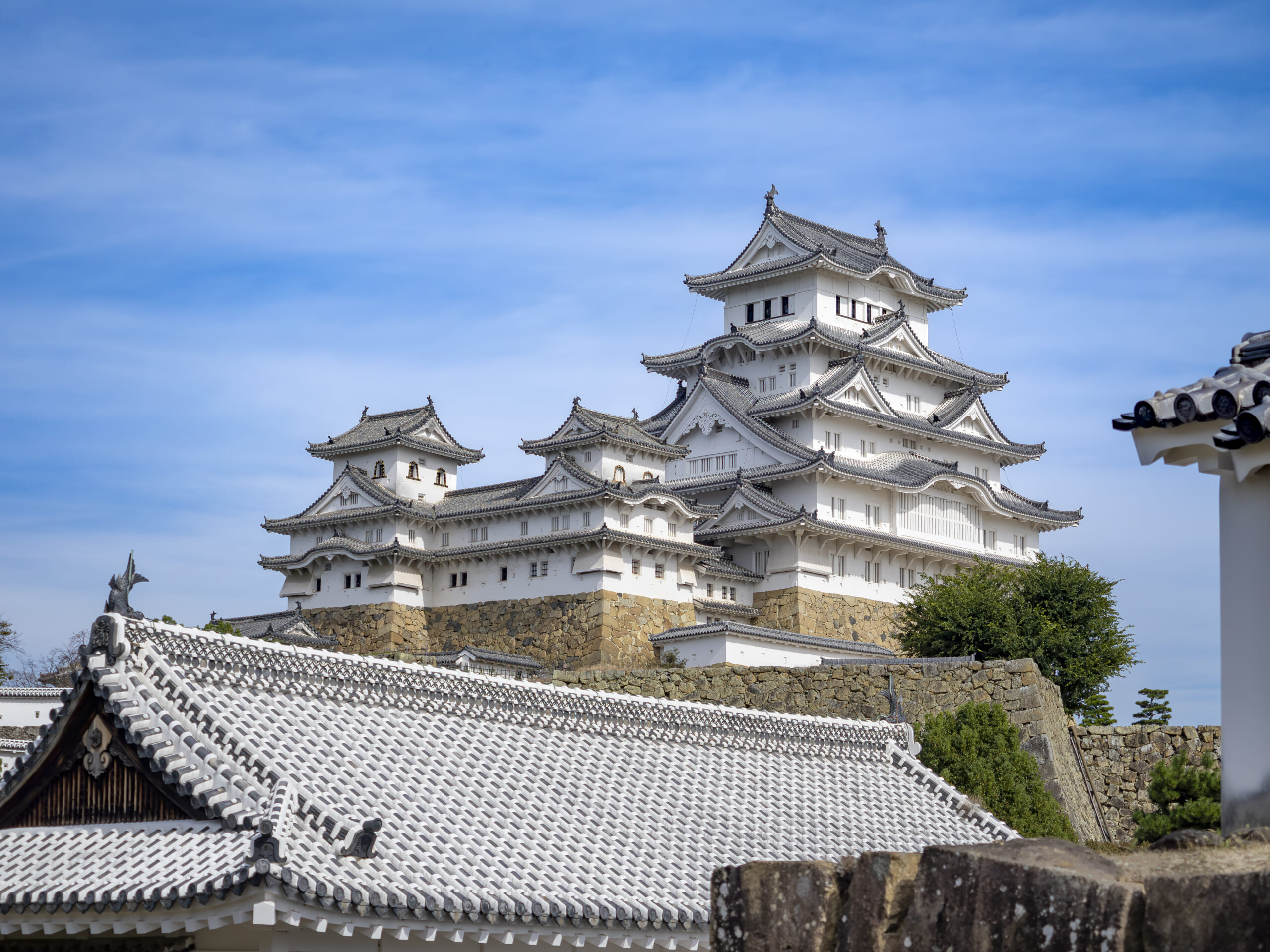 Himeji Castle's white keep seen from near the Nishinomaru South Gate ruins beneath a blue sky