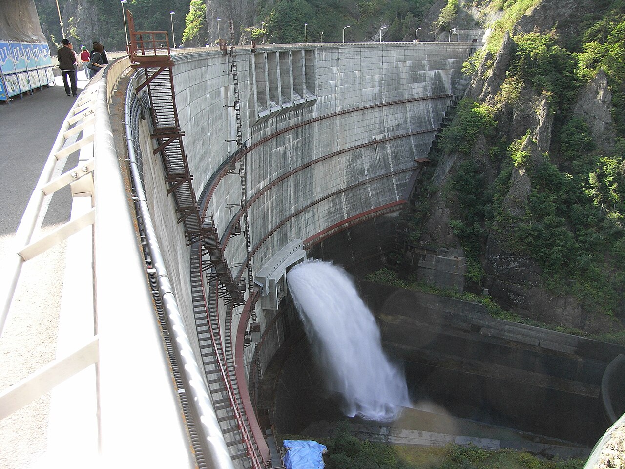 The curved wall of Hoheikyo Dam and water released downstream