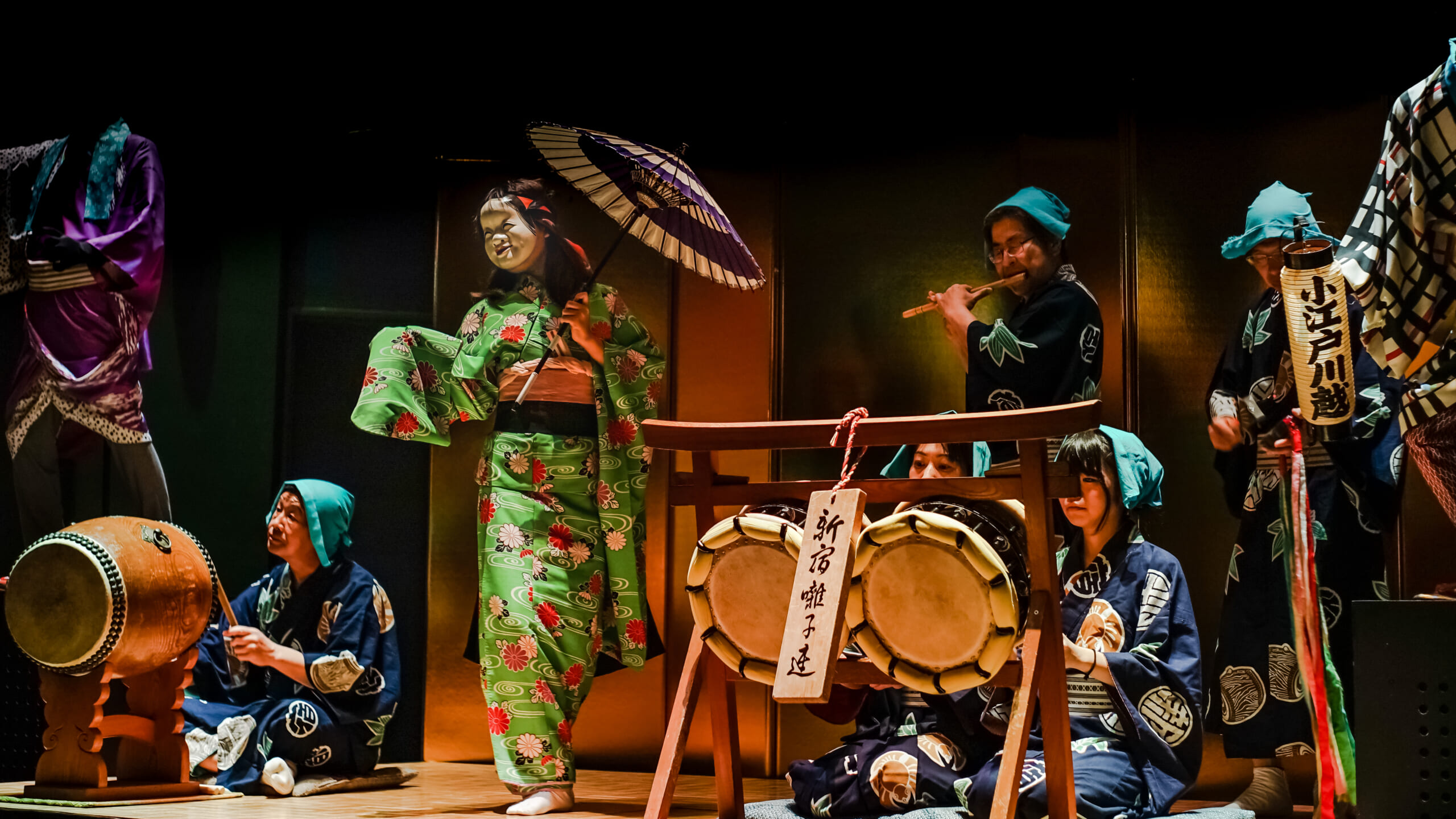 A masked dancer with flute and drum players performing at Kawagoe Festival Hall