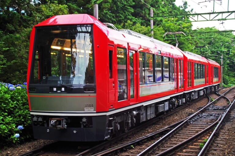 A red Hakone Tozan train travelling through the forest