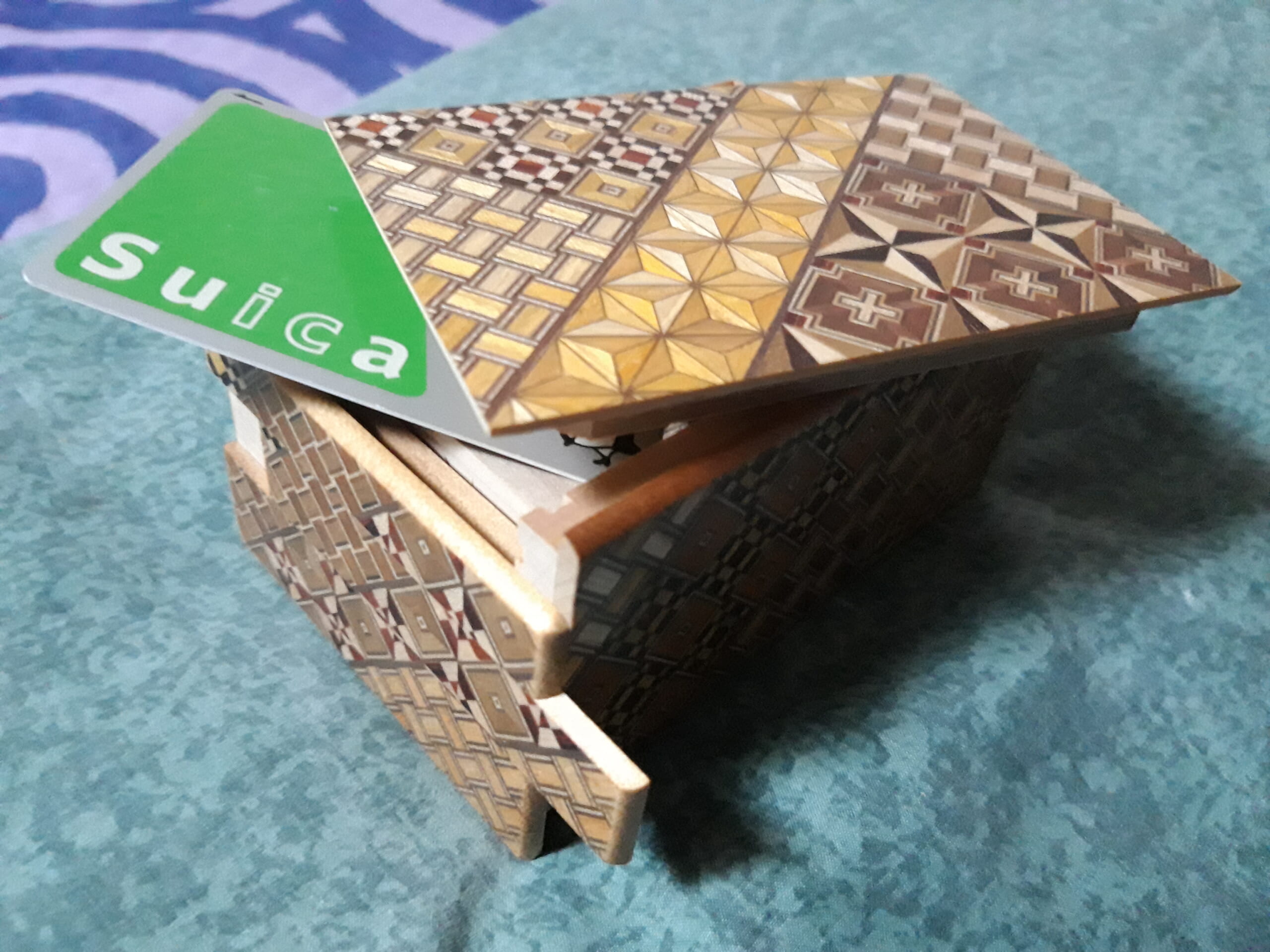 An open Japanese puzzle box with a Suica card showing its scale