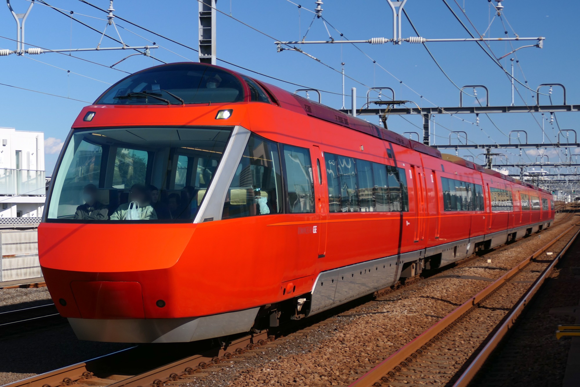 A red Odakyu Romancecar GSE on the railway