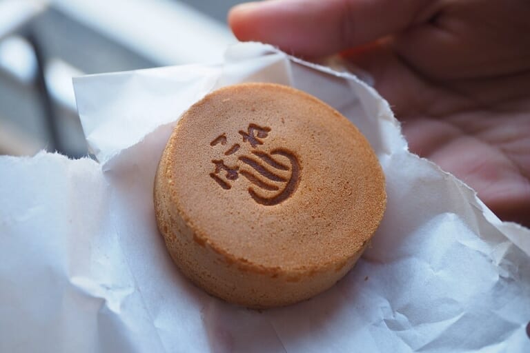 A Kikukawa Shoten baked manju held in its wrapper