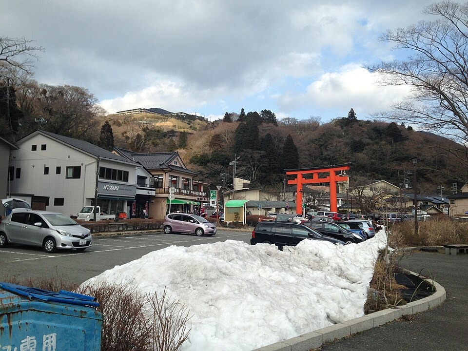 A torii on the snowy Hakone Shrine approach with Mount Futago beyond