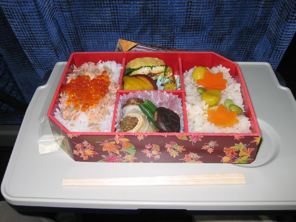 A seafood and egg bento on a train seat table