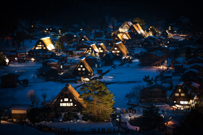 Snow-covered thatched houses illuminated at night in Shirakawa-go
