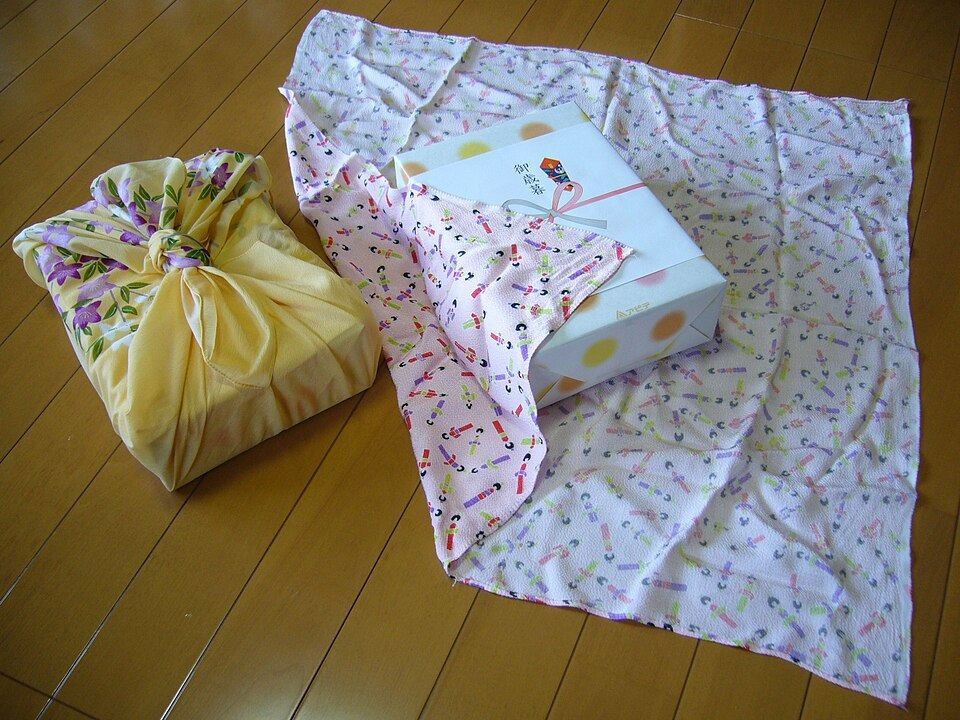 An unfolded furoshiki beside a cloth-wrapped gift