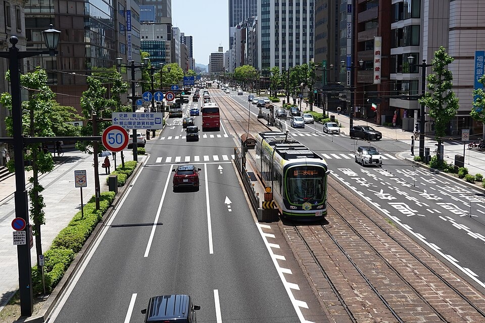 Trams travelling along tracks in the middle of a Hiroshima street
