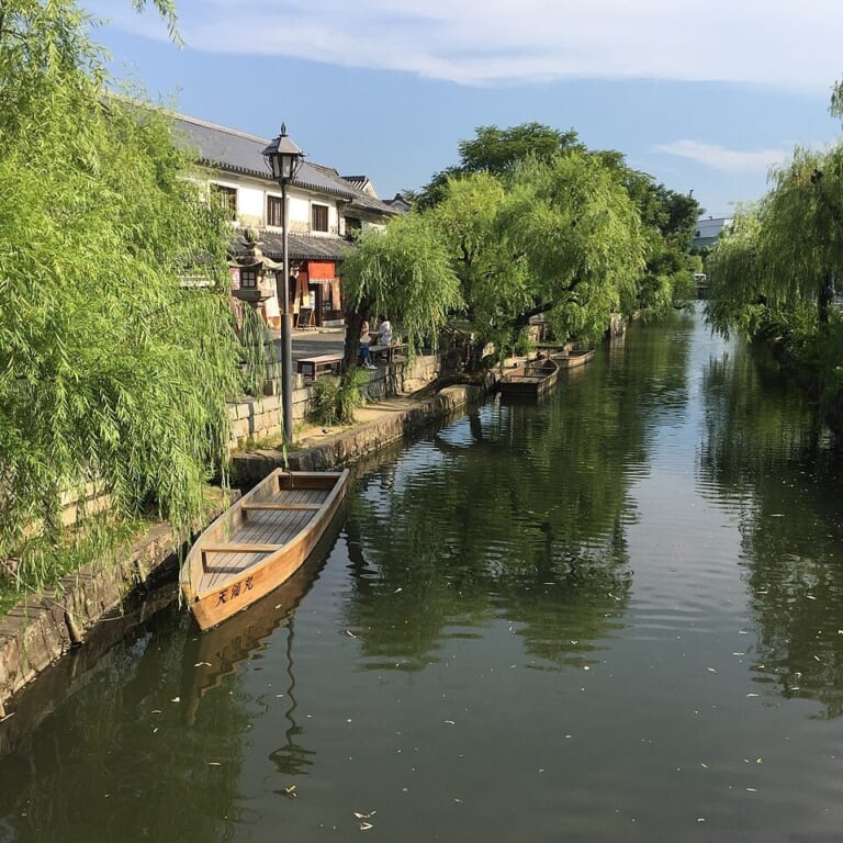 Willow trees and a wooden boat beside the canal in Kurashiki