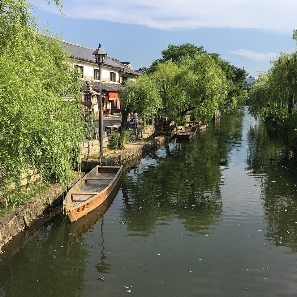Willow trees and a wooden boat beside the canal in Kurashiki