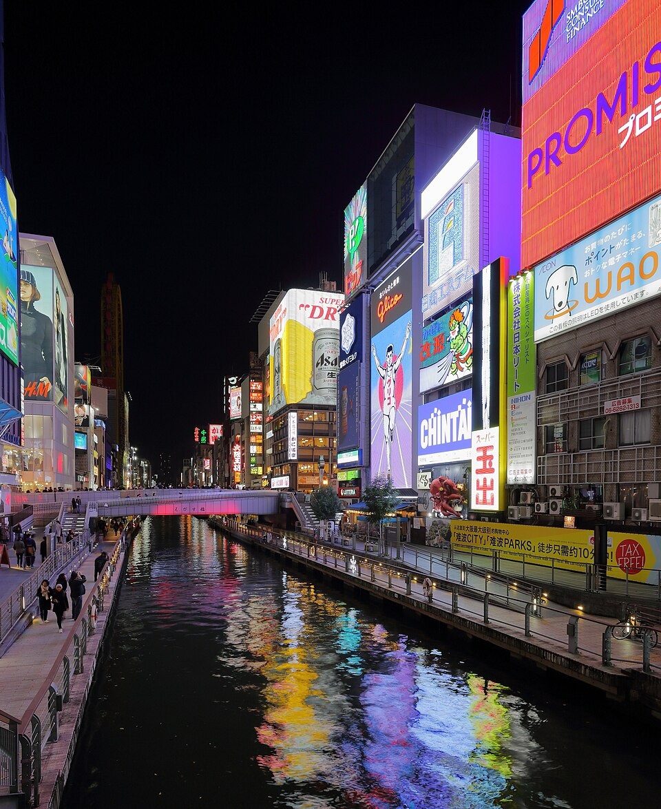 Illuminated signs and a walkway beside the Dotonbori Canal at night