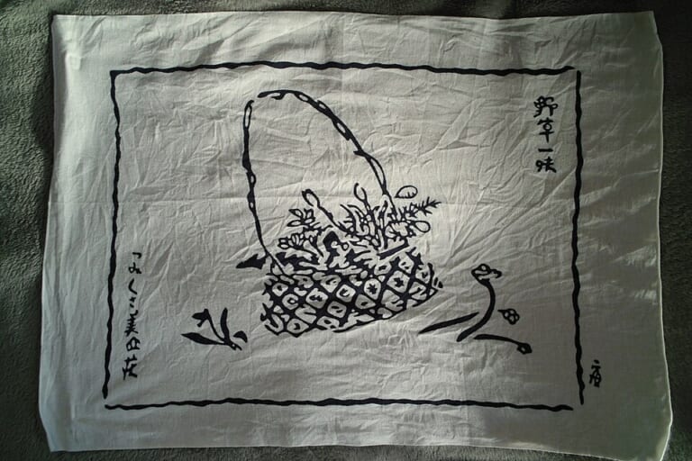 A basket and wild-plant design printed on a white tenugui