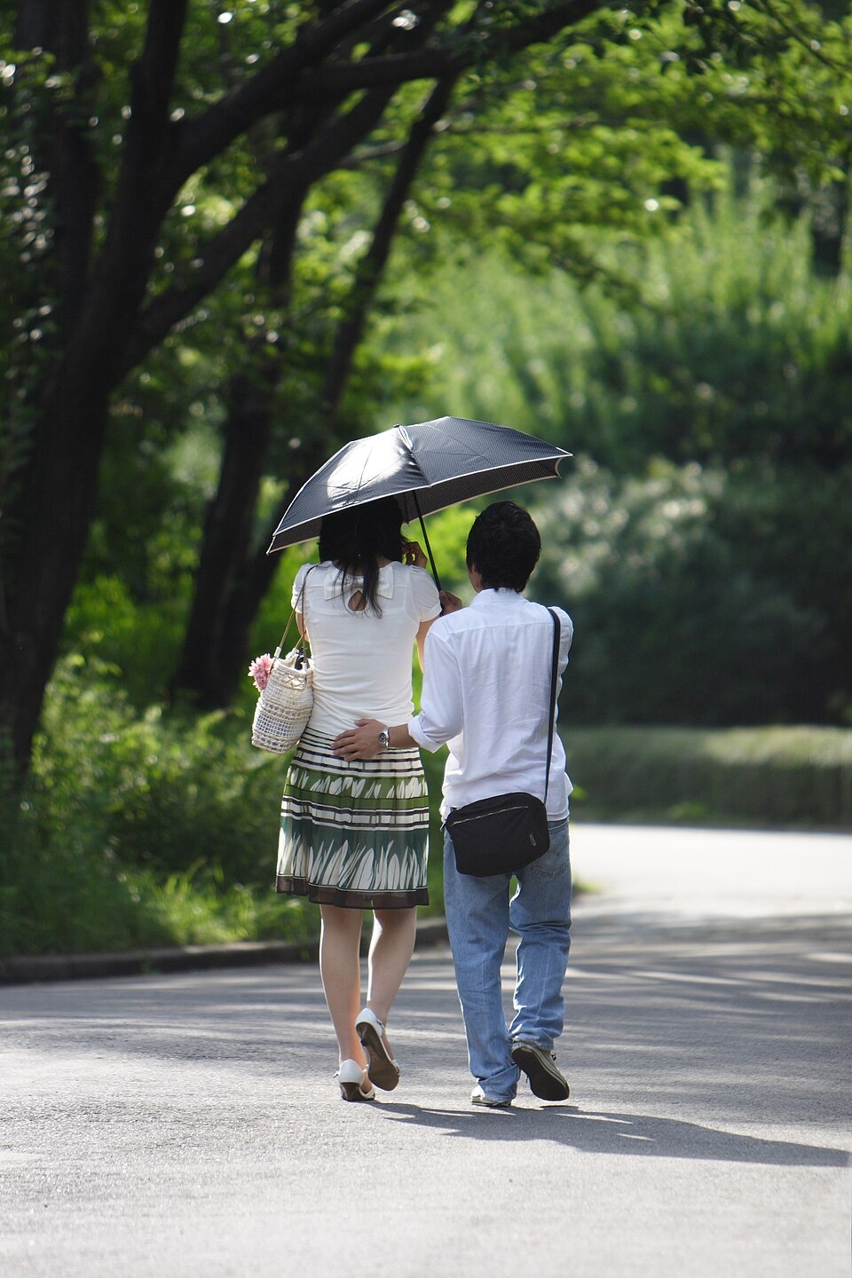 People walking beneath a parasol in the East Gardens of Tokyo Imperial Palace