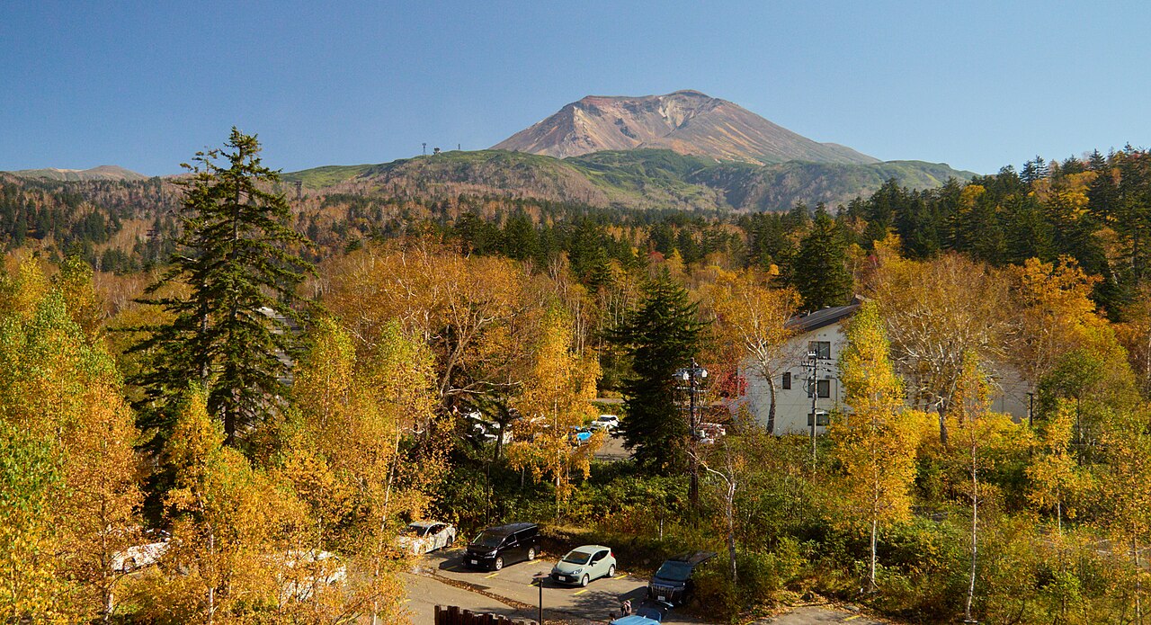 Autumn trees and buildings at Asahidake Onsen with the mountain behind