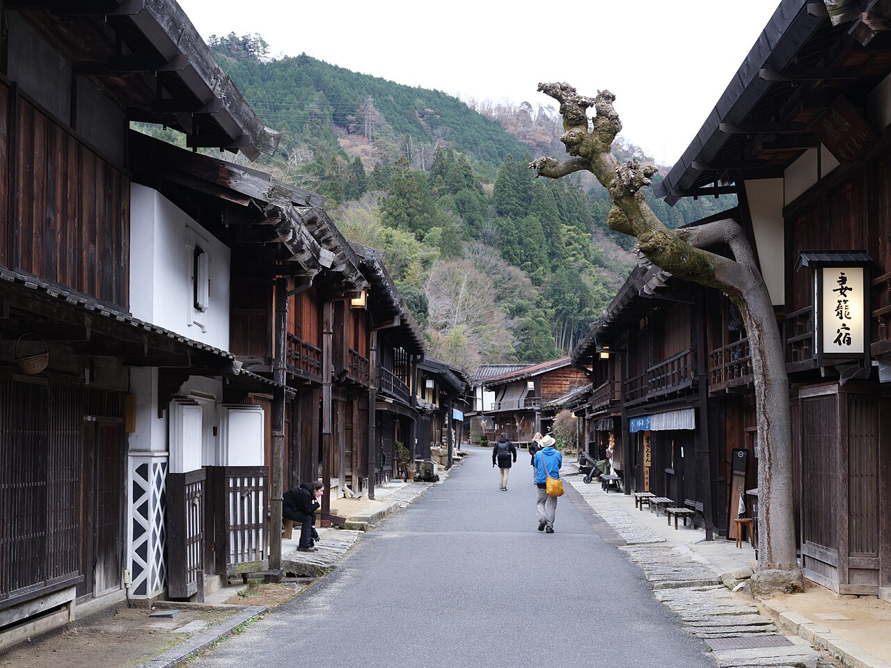 Wooden houses lining the street in Tsumago with wooded hills behind