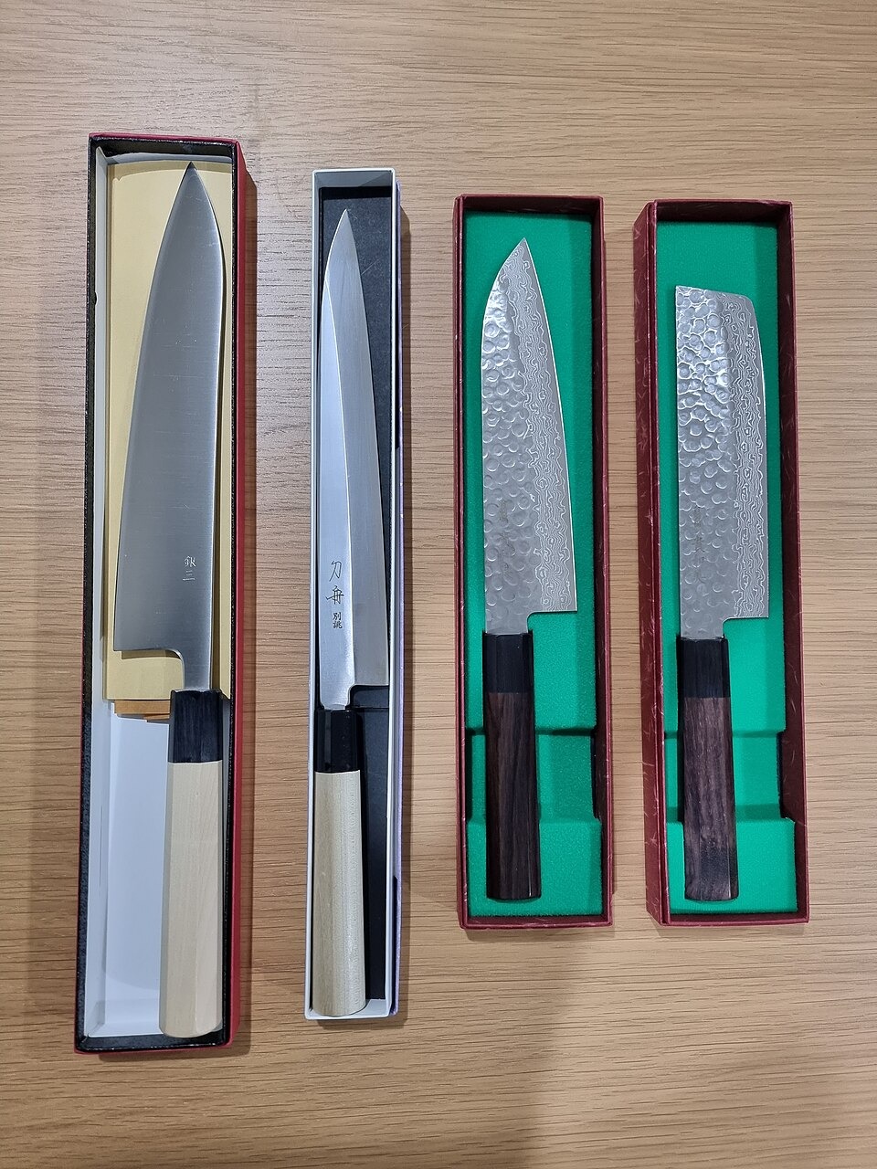 Gyuto, yanagiba, santoku and nakiri knives arranged on a wooden surface