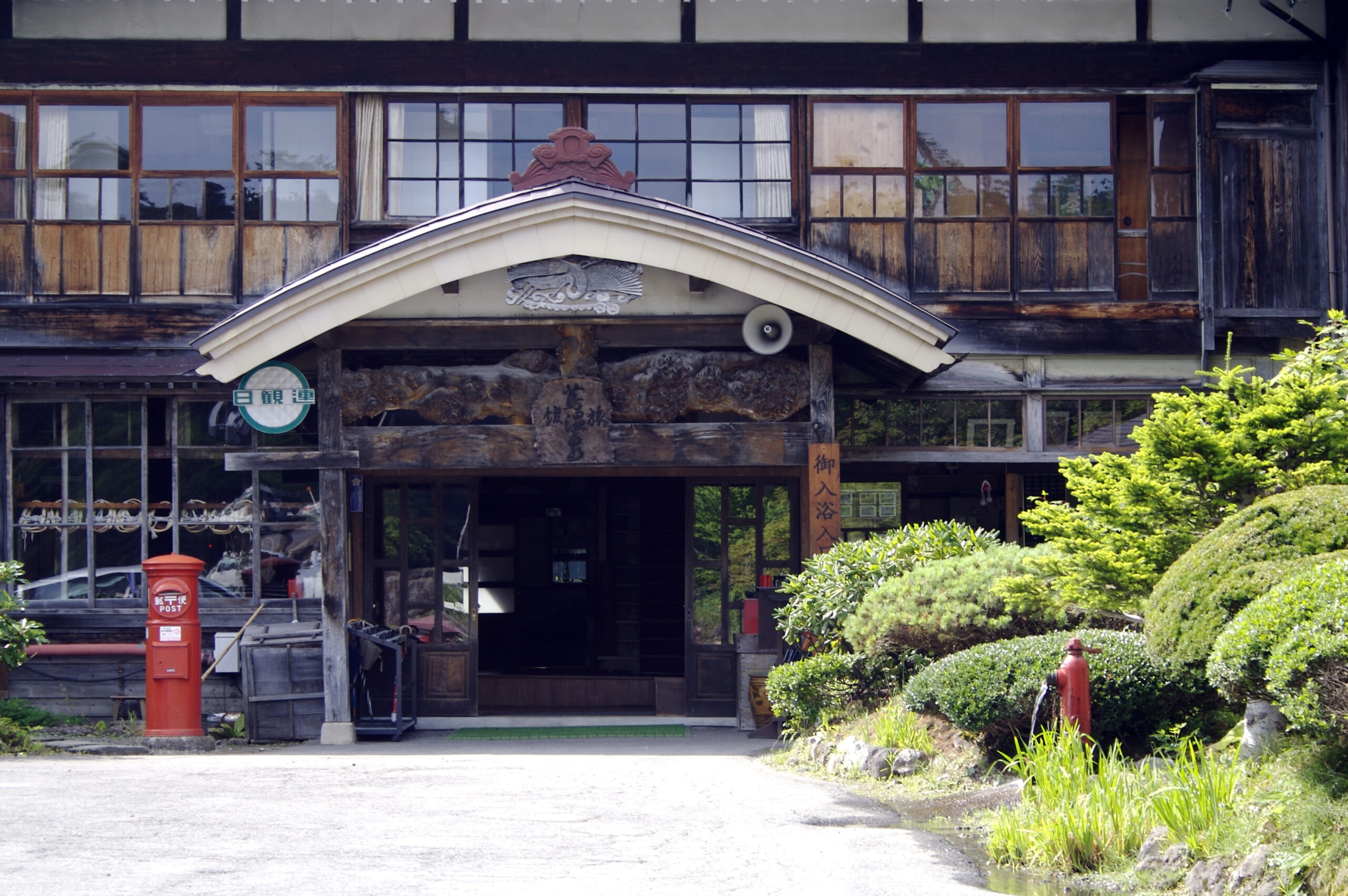 Wooden entrance of Tsuta Onsen Ryokan with a red postbox outside