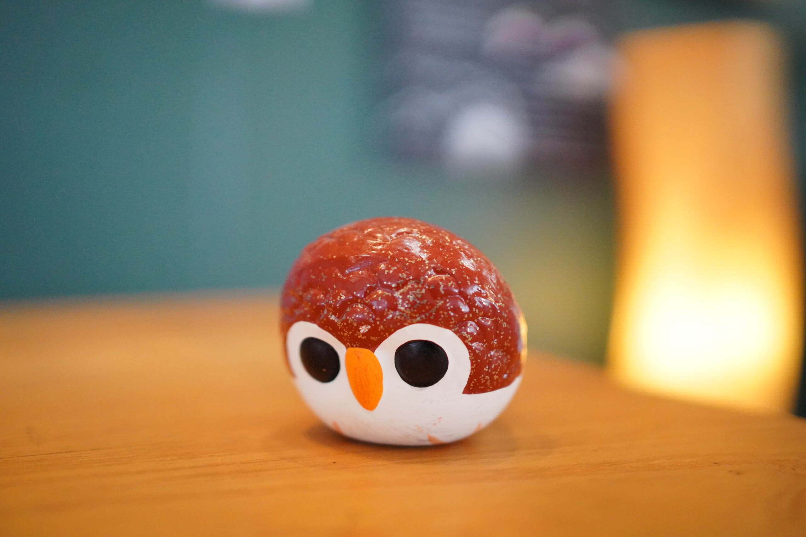 An owl-shaped Moma clay whistle on a wooden surface